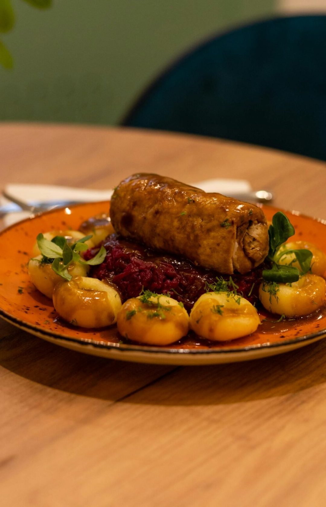 Deliciously plated gourmet dish featuring sausage and vegetables on a rustic wooden table setting.